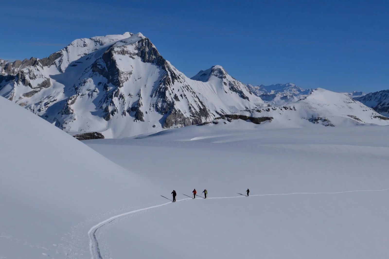 Skieurs de randonnée traversant un grand plateau enneigé face aux sommets de la Vanoise, au-dessus de Pralognan